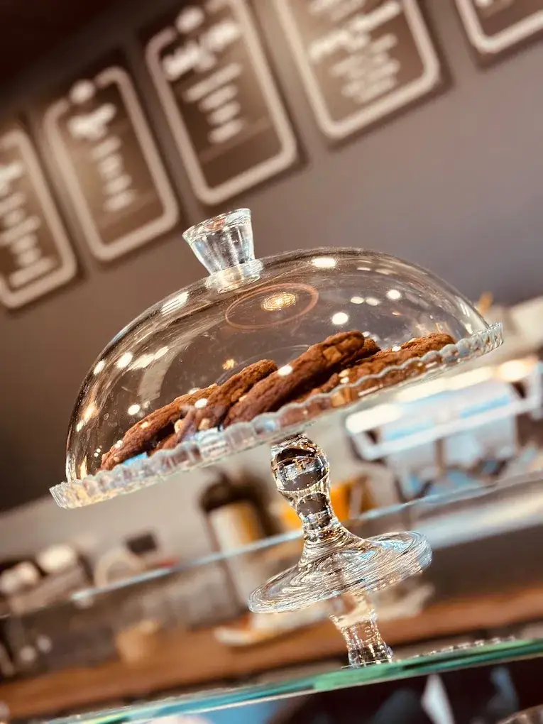 Des cookies sous une cloche en verre, avec les ardoises du menu en arrière-plan